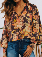 Load image into Gallery viewer, Person wearing a floral blouse with long sleeves and blue jeans.