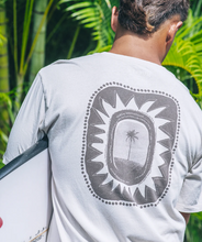 Load image into Gallery viewer, Person wearing a white t-shirt with a graphic design on the back, standing in front of green foliage.